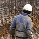 Construction worker looking at plans with fellow construction workers in background